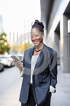 Smiling mature businesswoman using mobile phone in urban setting