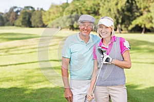 Smiling mature couple standing at golf course