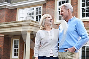 Smiling Mature Couple Standing Outside Home photo