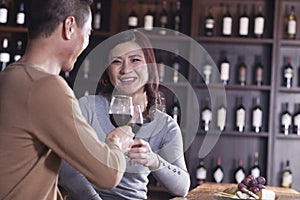 Smiling mature couple toasting and enjoying themselves drinking wine, focus on female