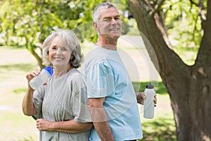 Smiling mature couple with water bottles at park