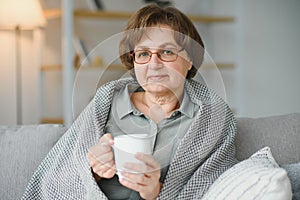 Smiling mature elder 65s woman sitting relaxing with cup of tea, coffee. Senior mid age stylish look woman with