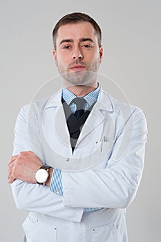 Smiling mature male doctor with crossed arms isolated on grey ba