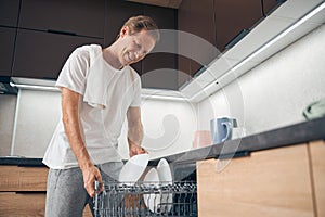 Smiling mature man being alone in the kitchen