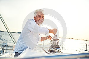 Mature man working a rope winch on his sailboat