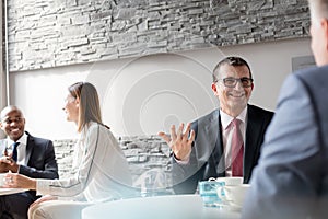 Smiling mature man talking with male colleague in office cafeteria