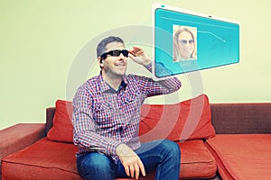 Smiling mature man using modern digital AI goggles for virtual call on hologram screen