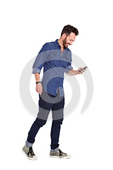 Smiling mature man walking and using mobile phone