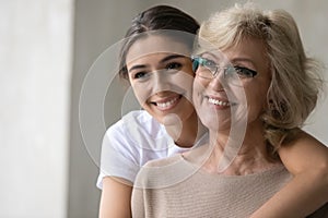 Smiling mature mother and adult daughter look in distance dreaming