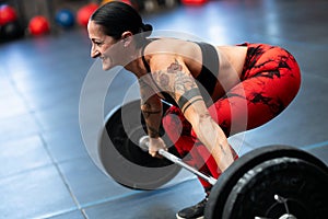 Smiling mature sportive woman weightlifting in a gym