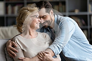 Smiling mature woman and adult son cuddling, enjoying tender moment