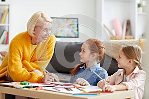 Smiling Mature Woman Drawing with two Kids