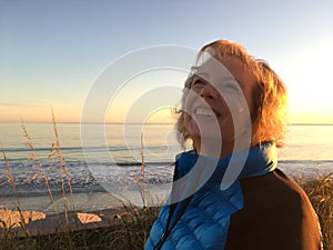 Smiling mature woman enjoying a sunset by the Ocean