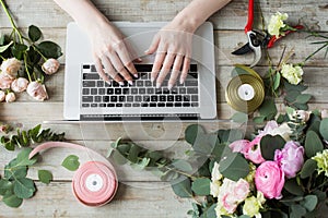 Smiling Mature Woman Florist Small Business Flower Shop Owner. She is using her telephone and laptop to take orders for