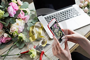 Smiling Mature Woman Florist Small Business Flower Shop Owner. She is using her telephone and laptop to take orders for