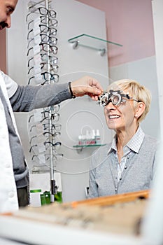 Smiling mature woman having eyesight exam and diopter measurement at the ophthalmology clinic