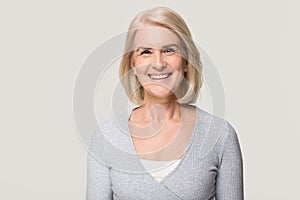 Smiling mature woman looking at camera isolated on grey background