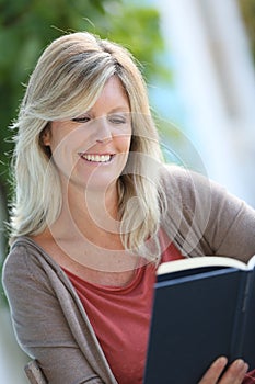 Smiling mature woman reading book