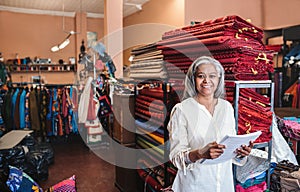 Smiling mature woman reading paperwork in her fabric shop