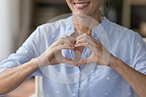 Smiling mature woman showing symbol of love, cropped shot