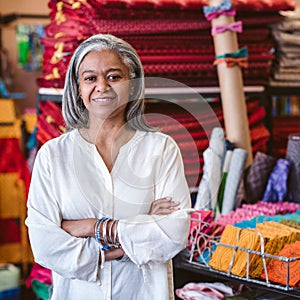 Smiling mature woman standing by textiles in her fabric shop