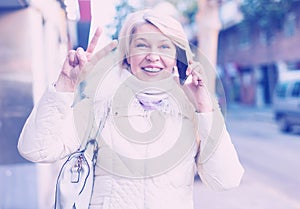 Smiling mature woman talking on phone and hand up