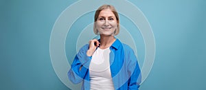 smiling mature woman thinking brilliant idea on blue background with copyspace