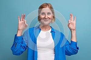 smiling mature woman thinking brilliant idea on blue background with copyspace