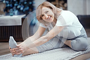 Smiling mature woman is touching her toes