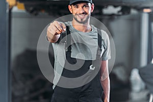 smiling mechanic holding car key in auto