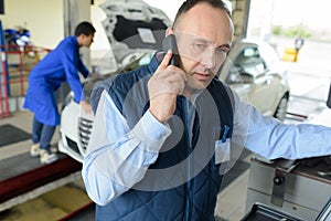 Smiling mechanic on phone at repair garage