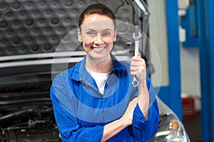 Smiling mechanic showing a wrench