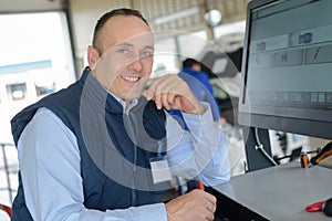 Smiling mechanic using computer at repair garage