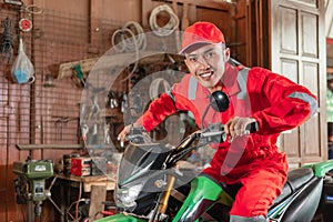 Smiling mechanic wearing wearpack and hat riding motorbike while trying out dirt bike brakes