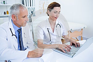 Smiling medical colleagues working with laptop