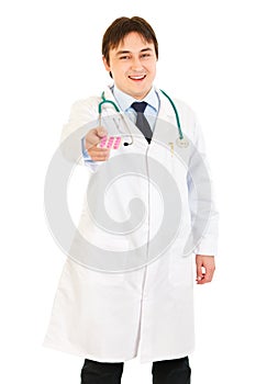 Smiling medical doctor giving pack of pills