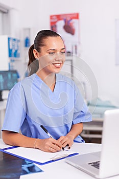 Smiling medical nurse writing notes