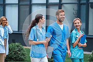 smiling medical students and lecturer walking on street