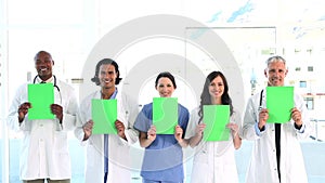Smiling medical team showing blank papers