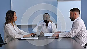 Smiling medical team using laptop to work, discussing new medicine photo