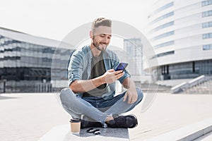 Smiling men texting on his mobile phone outdoors, Student man using smartphone in a city.