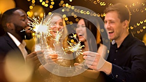 Smiling men and women holding sparklers, festive atmosphere, luxury lifestyle