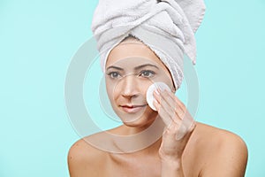 Smiling mid 30s woman removing make up using a cotton pad. Photo of attractive caucasian woman with healthy skin.