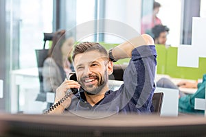 Smiling mid adult businessman talking on phone in office