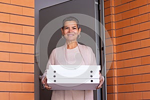 Smiling mid adult woman with pizza boxes at entrance
