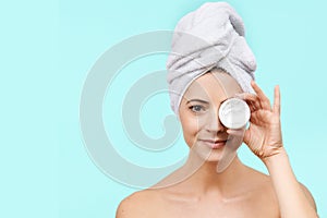 Smiling mid 30s woman holding moisturizing cream in front of her face. Beauty and Skincare concept.