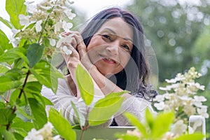 A smiling midage woman in a green flower garden is expressing happiness and joy of midlife hormonal changes and