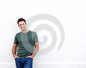 Smiling middle age man leaning against white wall