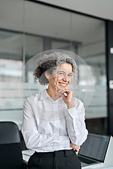 Smiling middle aged business woman leader standing in office, vertical portrait.