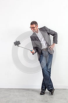 Smiling middle aged businessman taking selfie with stick for fun